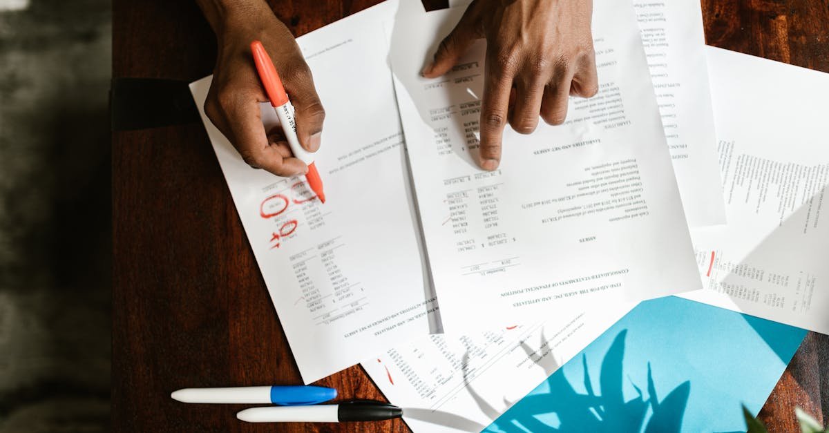 Mãos de uma pessoa revisando documentos financeiros e contratos sobre uma mesa de madeira. — Foto: RDNE Stock project