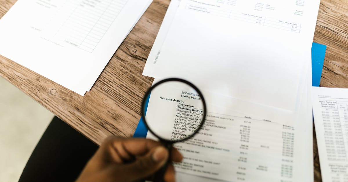 Mão segurando uma lupa sobre documentos e faturas financeiras em uma mesa de madeira. — Foto: RDNE Stock project