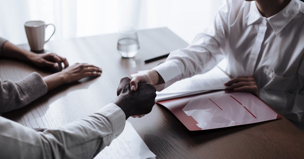 Duas pessoas em reunião profissional, uma assinando documentos sobre mesa. — foto: ron lach