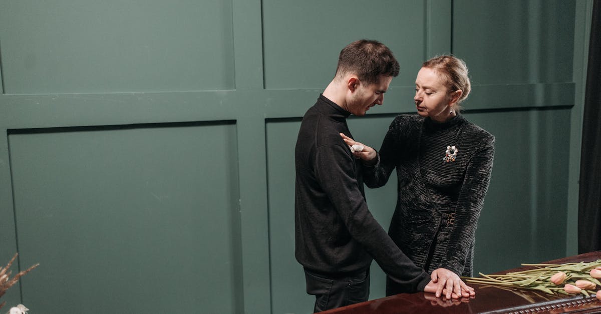 Homem e mulher vestidos de preto em um funeral, com as mãos sobre o caixão em sinal de luto. — Foto: Pavel Danilyuk