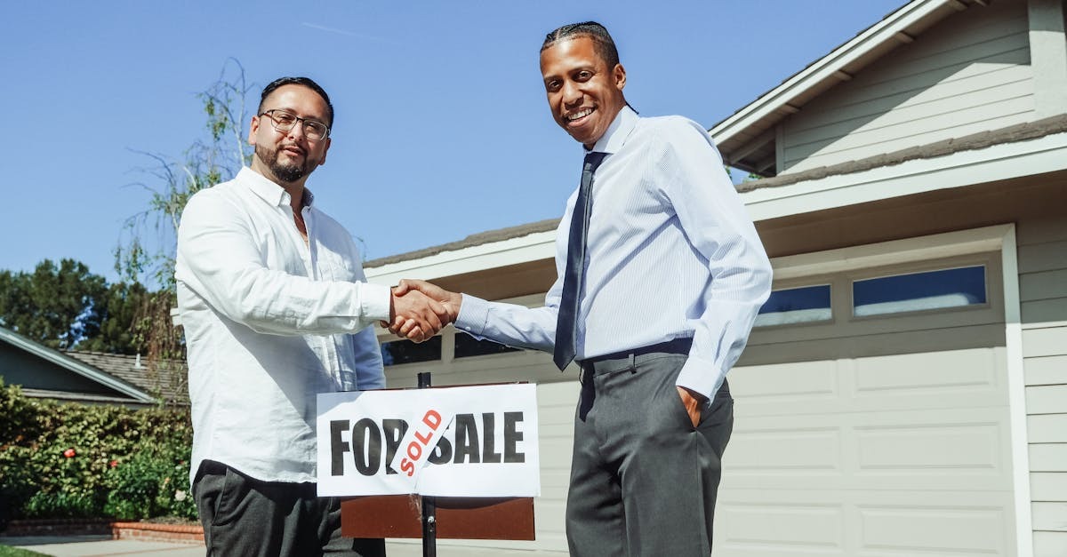 Dois homens celebrando a venda de uma propriedade com um cartaz 'FOR SALE'. — Foto: Kindel Media