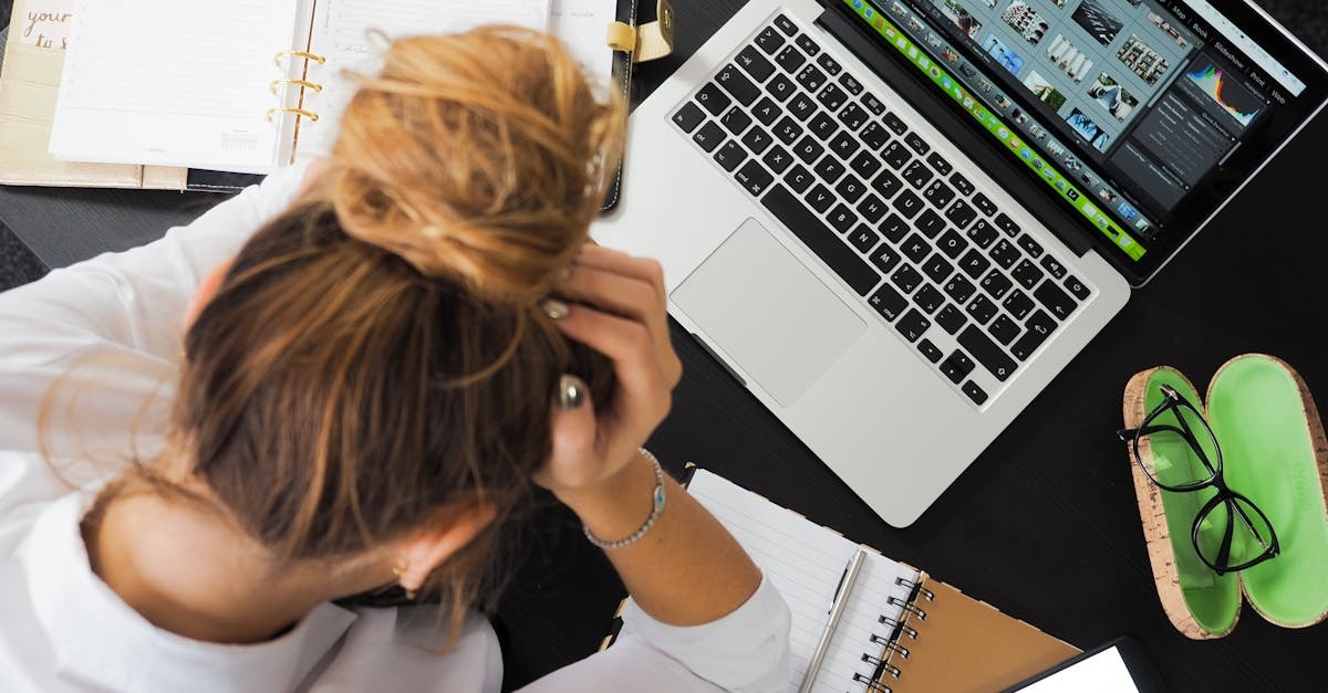 Mulher com cabelo em coque, olhando para um laptop e documentos em uma mesa de trabalho. — Foto: energepic.com