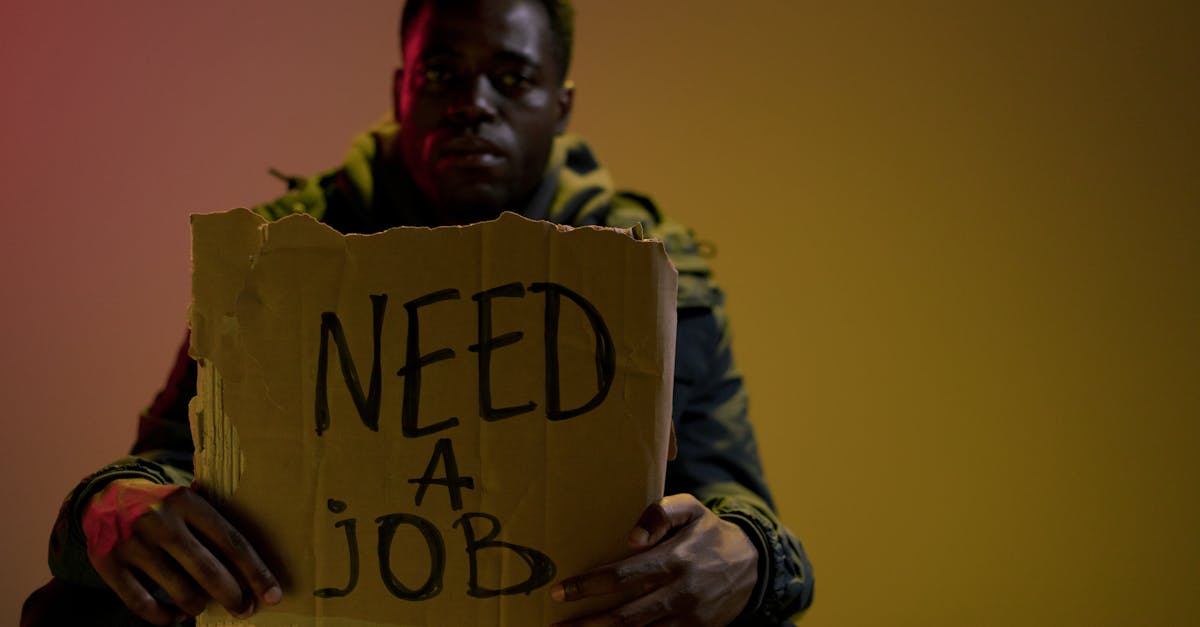 Homem segurando cartaz de papelão com a frase 'Need a job' em inglês. — Foto: Ron Lach