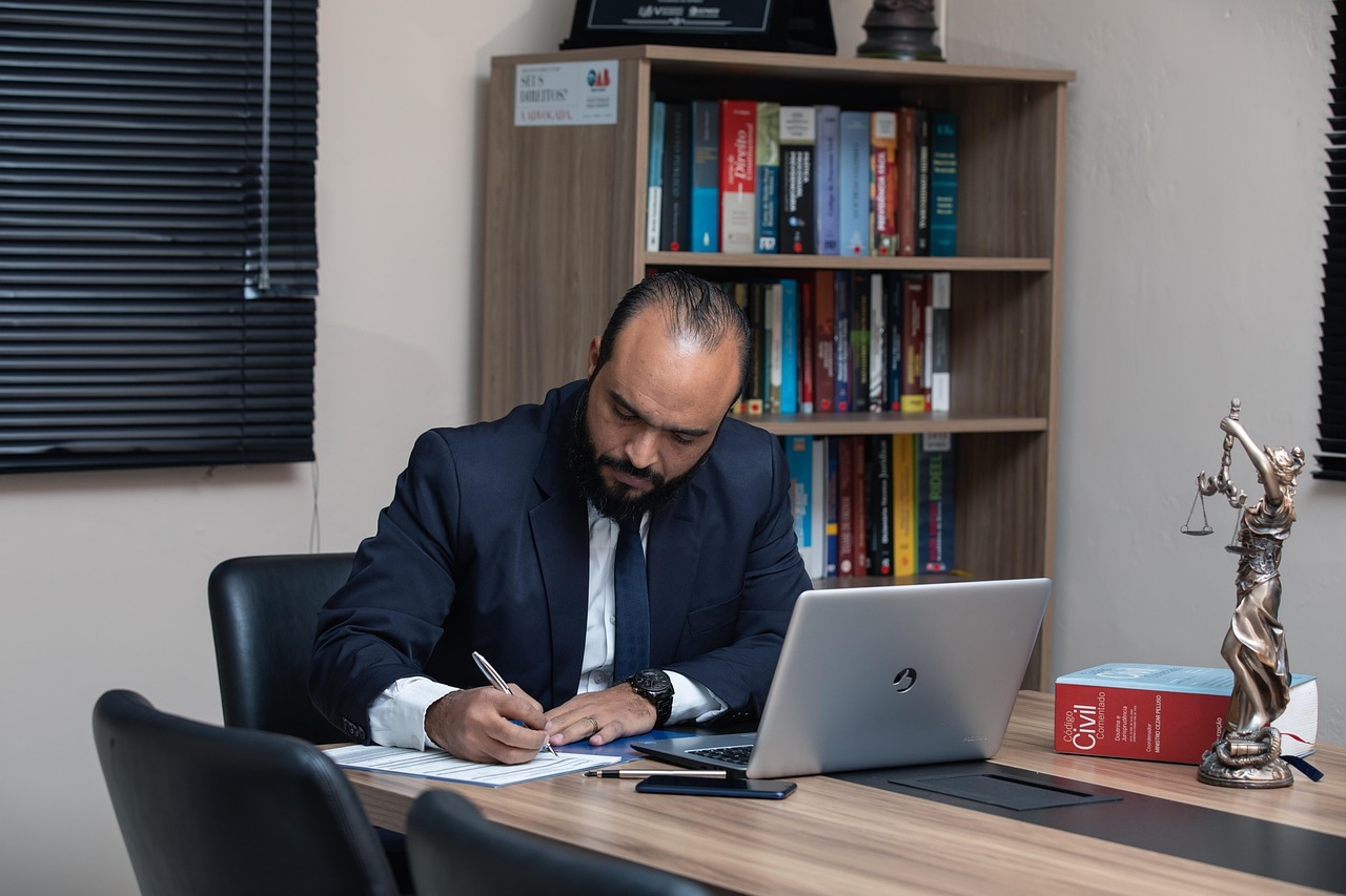 Advogado escrevendo em frente a laptop em escritório — Foto: advogadoaguilar
