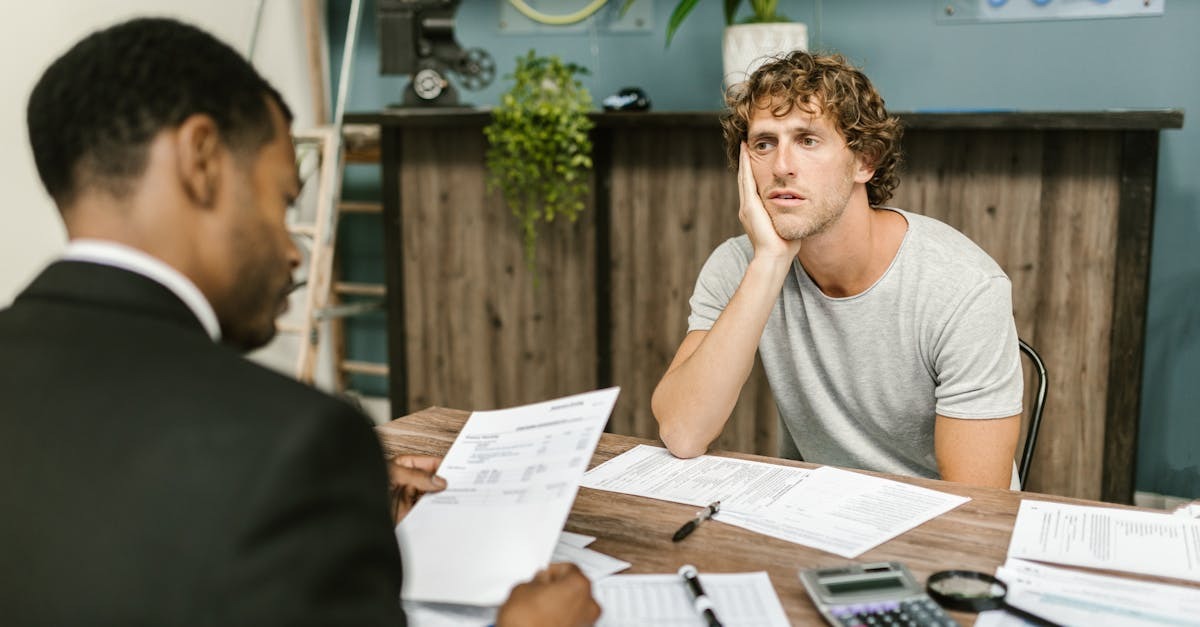Homem em terno discutindo documentos financeiros com outro homem em ambiente de escritório. — Foto: RDNE Stock project
