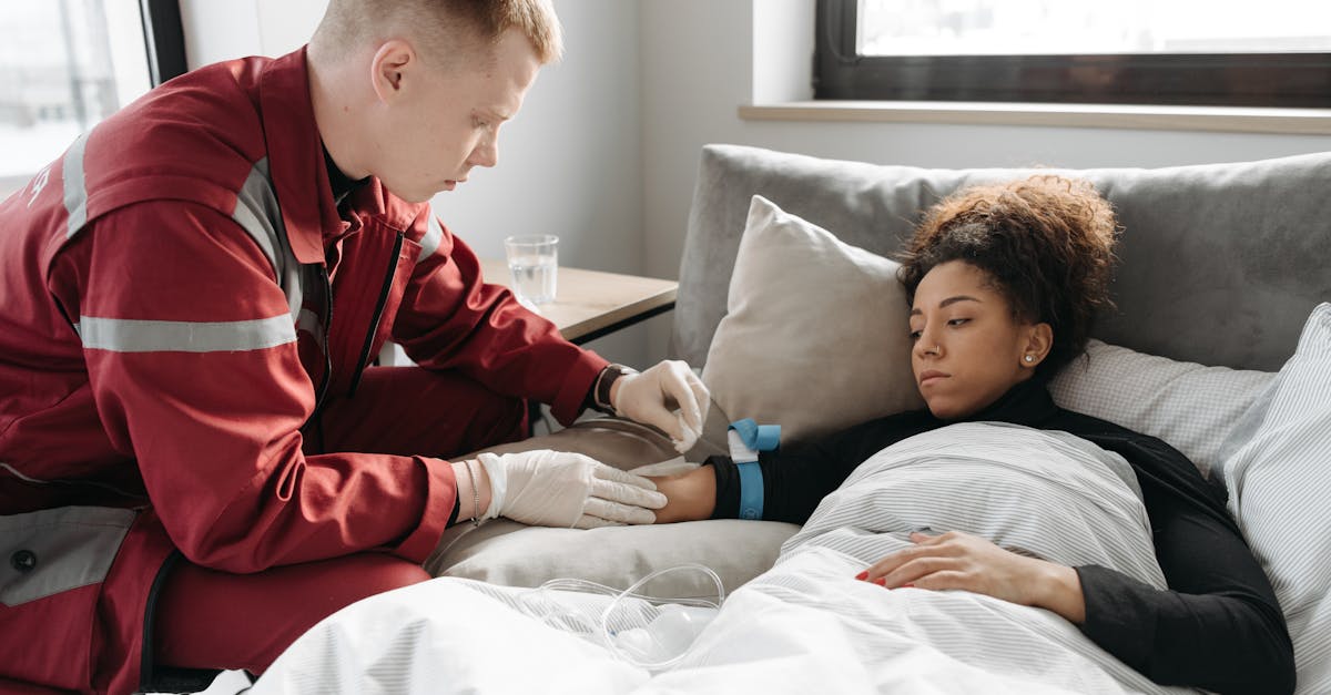 Profissional de saúde em uniforme vermelho realizando procedimento em paciente deitada na cama. — Foto: Pavel Danilyuk