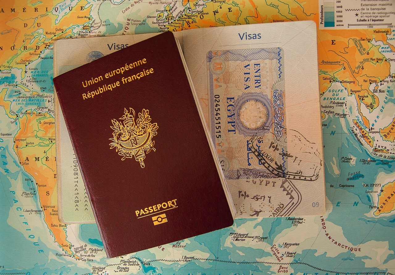 Passaporte francês aberto sobre um mapa-múndi, exibindo páginas com carimbos de vistos de viagem. — Foto: jackmac34