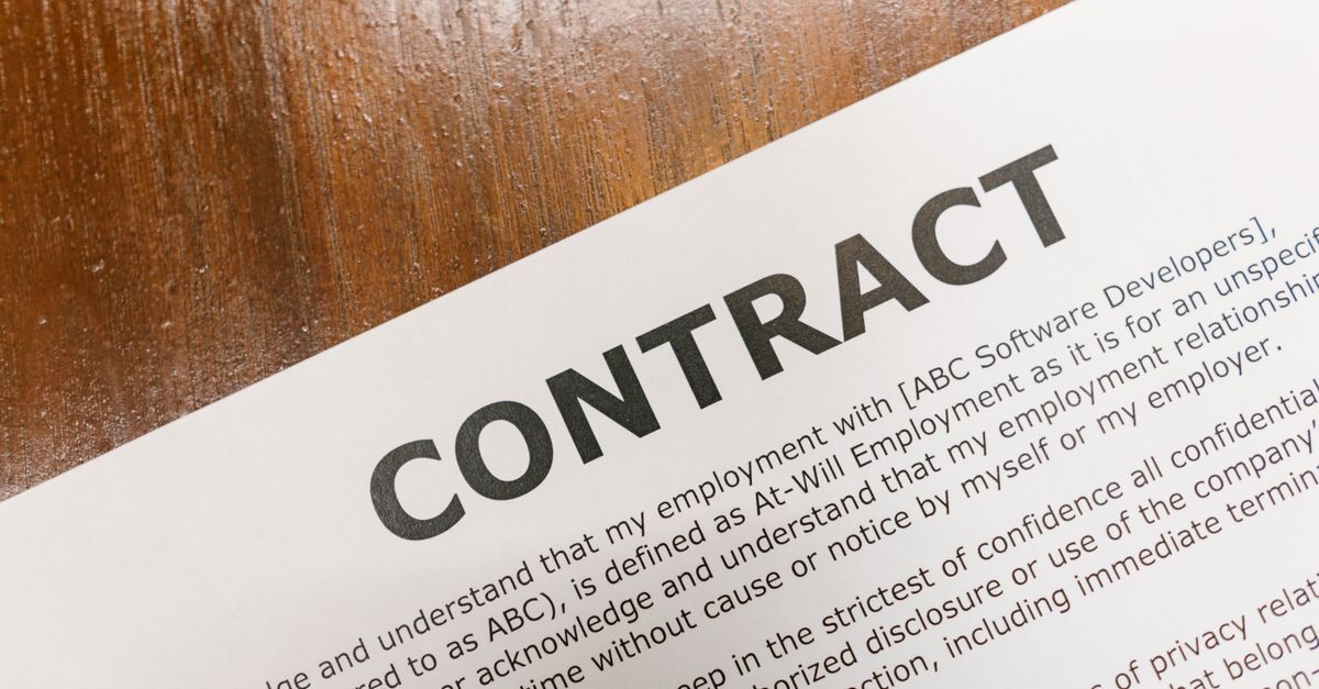 Papel com contrato de trabalho em destaque sobre mesa de madeira — foto: rdne stock project