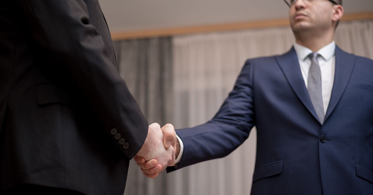 Doing business and investing in brazil as a foreigner complete guide inline 2 214646 1781601062 Dois homens em trajes completos apertando mãos em um ambiente de escritório. — foto: george morina