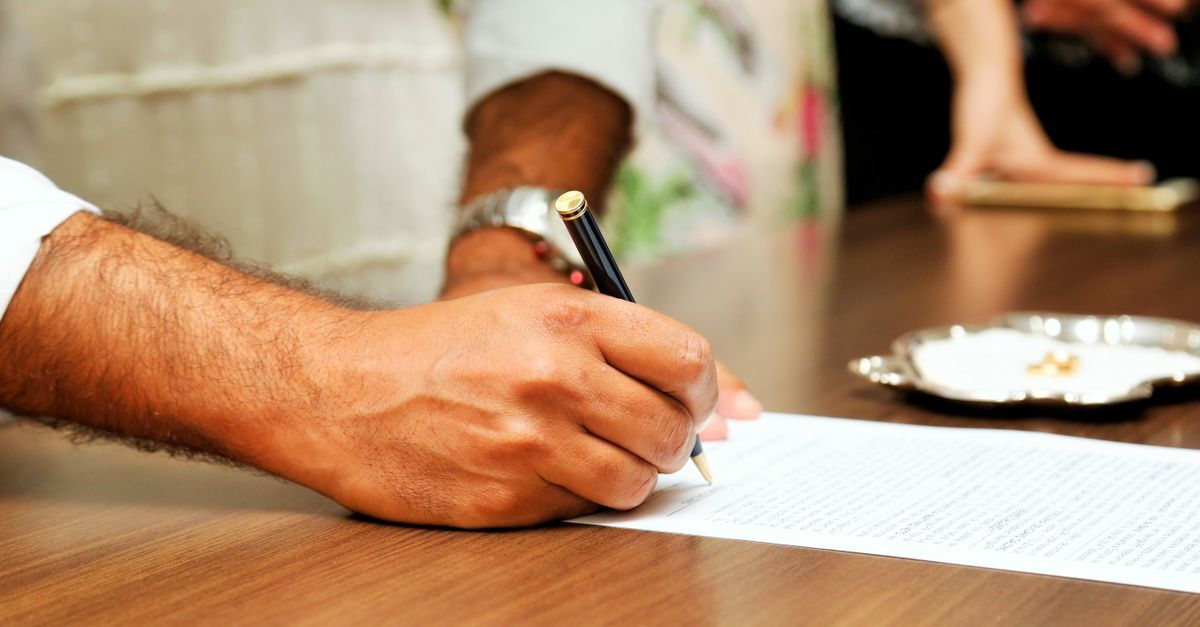 Mão segurando uma caneta escrevendo em um papel sobre uma mesa de madeira. — foto: vidal balielo jr.