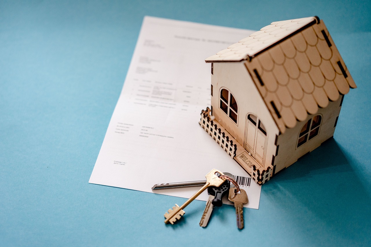Casa modelo, chaves e documentos sobre fundo azul, simbolizando compra e investimento imobiliário. — foto: oleksandrpidvalnyi