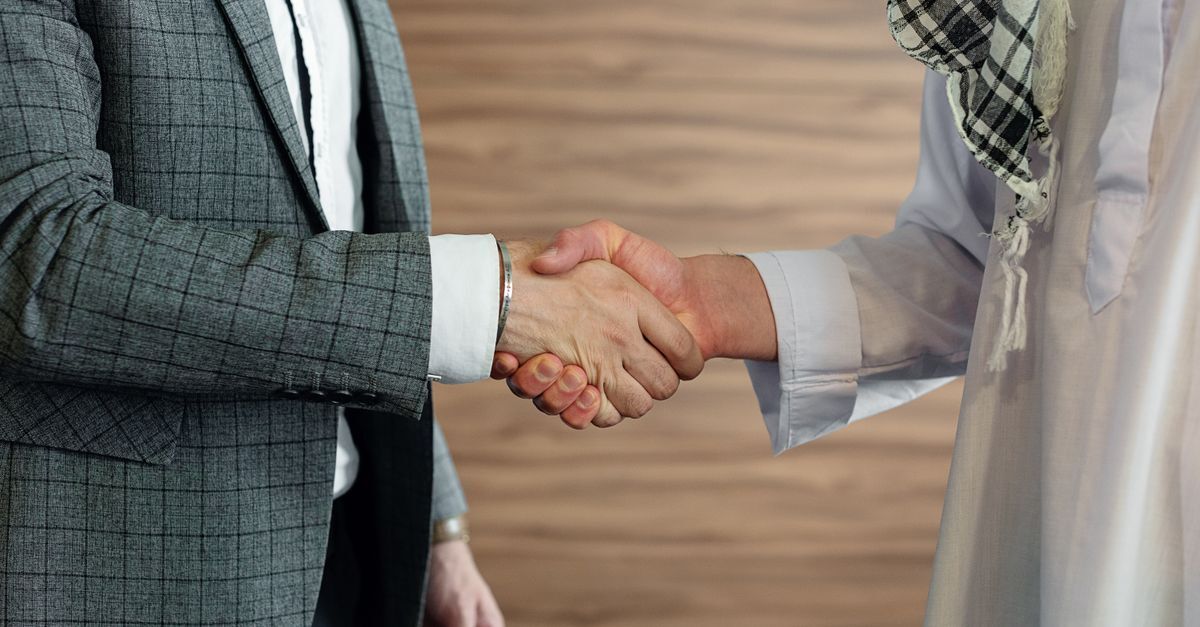 Brazil as a second base for turkish entrepreneurs inline 1 436565 1784306282 Dois homens em aperto de mãos, um em terno e outro em roupas tradicionais, simbolizando reunião de negócios.