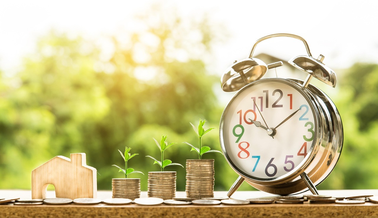 Brazil residency for egyptian entrepreneurs and real estate investors inline 1 453515 1784651740 Relógio despertador, moedas e casa de madeira em uma mesa