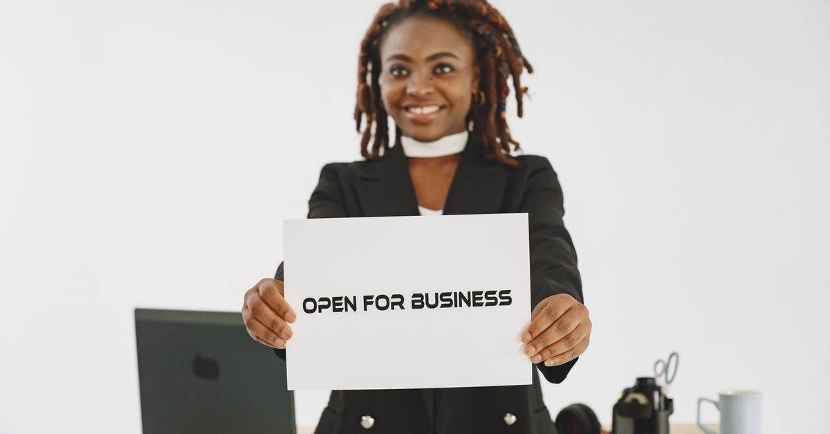 Brazilian residency and passport planning for south african entrepreneurs inline 1 384437 1783701469 Mulher em terno segurando um cartaz 'open for business' em um escritório.