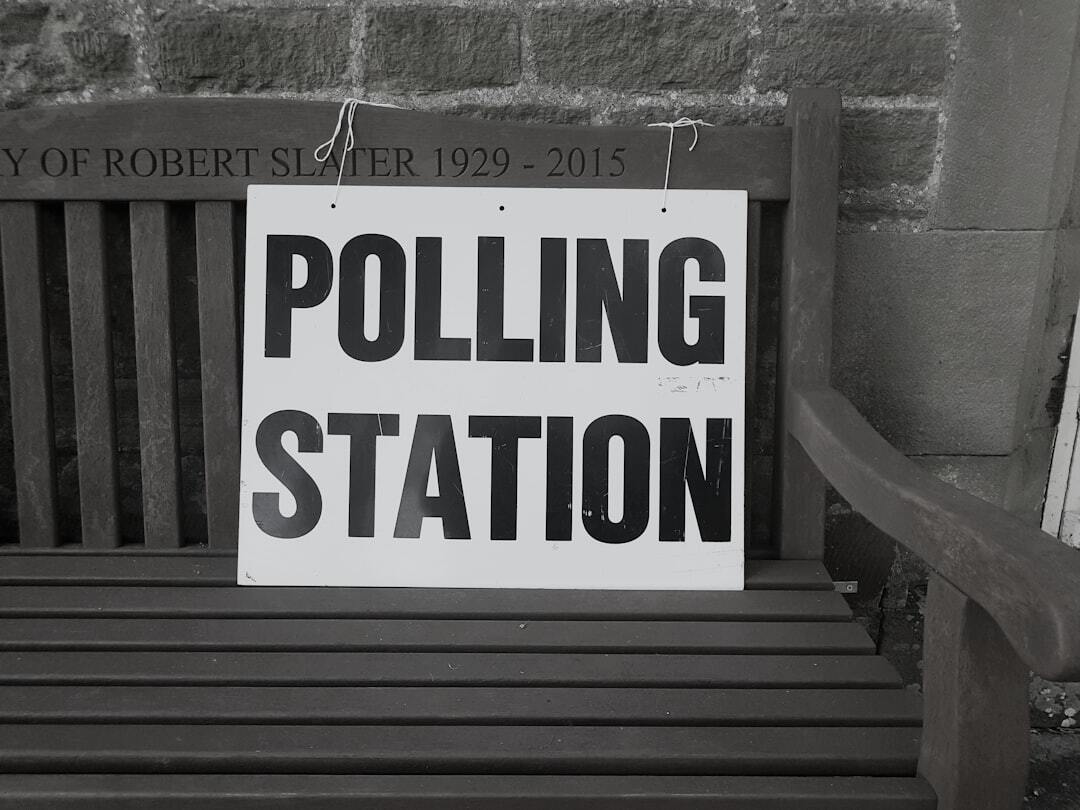 Placa branca com a inscrição 'polling station' em letras pretas apoiada em um banco de madeira.