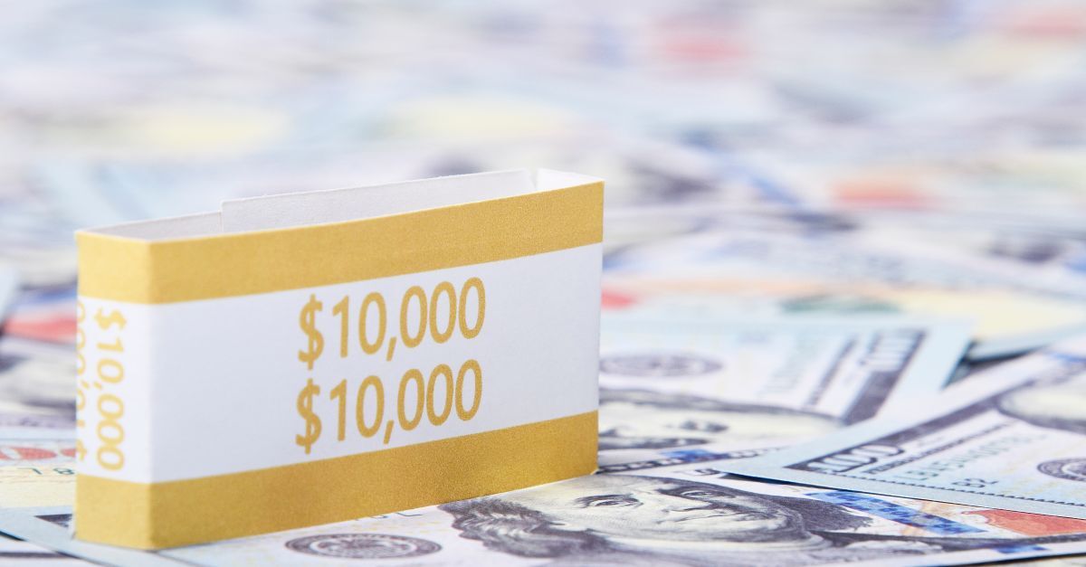 Caixa com $10. 000 sobre uma pilha de notas de dólar.