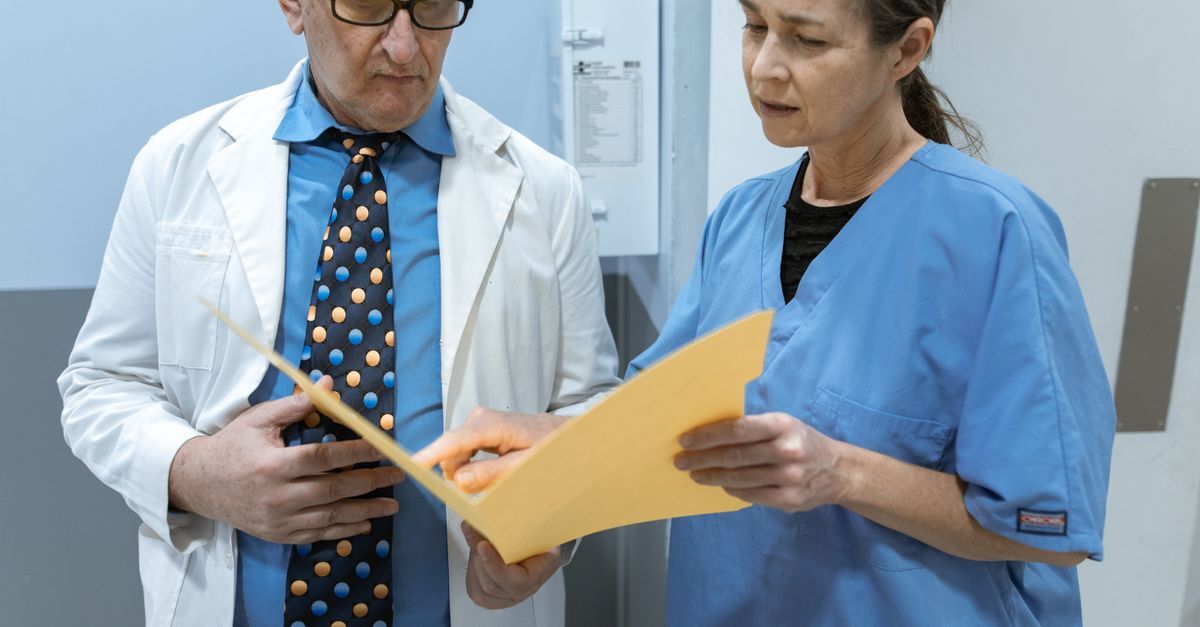 Médico e enfermeira analisando documentos juntos em ambiente hospitalar.