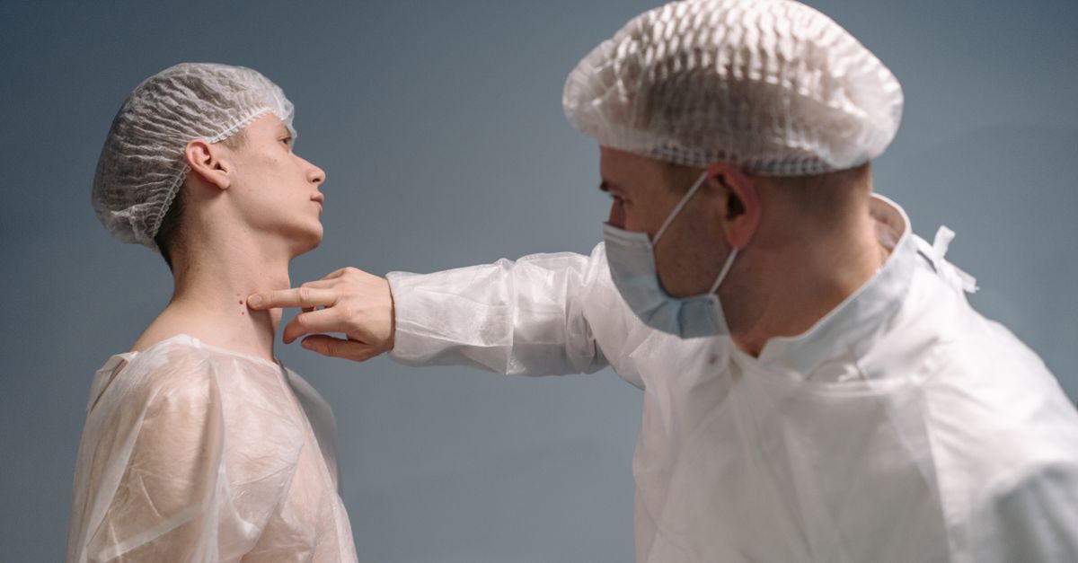 Cid c43 melanoma afastamento auxilio doenca e aposentadoria inline 2 436939 1784311897 Médico de máscara e touca examinando uma pinta no pescoço de um paciente em ambiente clínico.