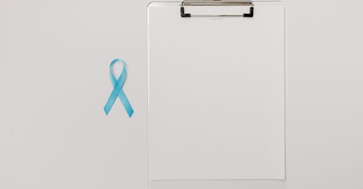 Cid c61 cancer de prostata afastamento auxilio doenca e aposentadoria inline 1 392900 1783793537 Laço azul de conscientização do câncer de próstata ao lado de uma prancheta branca com papel em fundo claro.