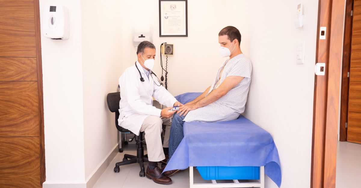 Médico e paciente em uma consulta médica, ambos usando máscaras.
