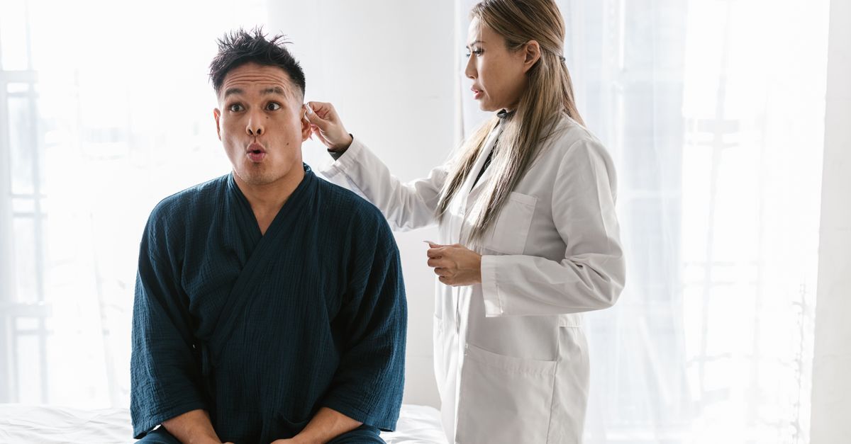 Médica examinando paciente sentado, discutindo condição médica.