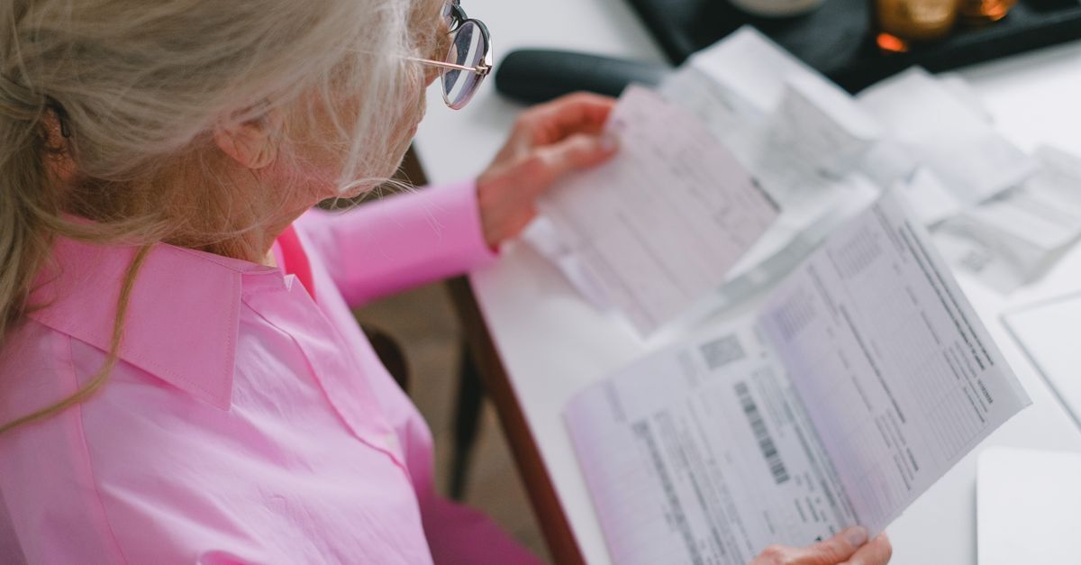 Mulher idosa analisando documentos em um escritório.