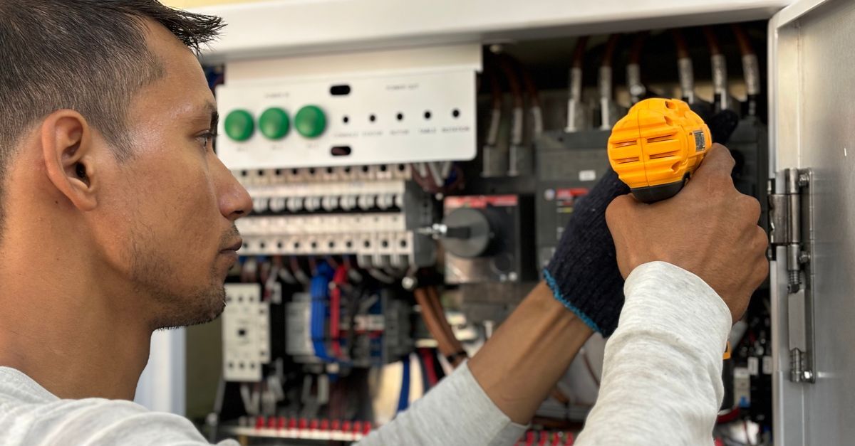Devolucao de produto inline 1 429071 1784212832 Técnico de perfil usando parafusadeira amarela para consertar um painel elétrico com fiação exposta.