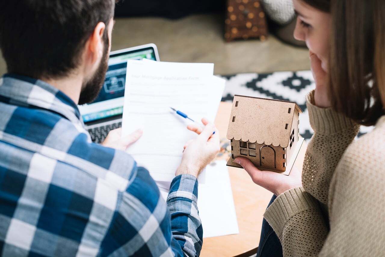 Pessoa analisando documentos e modelo de casa em uma reunião profissional. — foto: thedivorcelawfirm