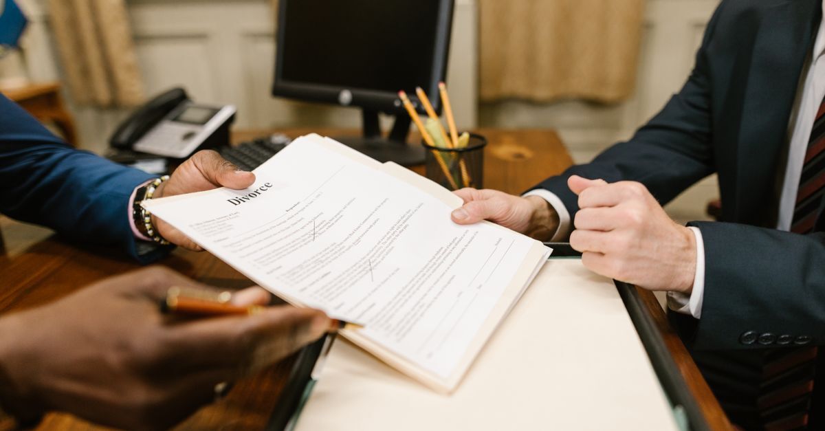 Duas pessoas em terno analisando documentos em uma mesa de escritório.