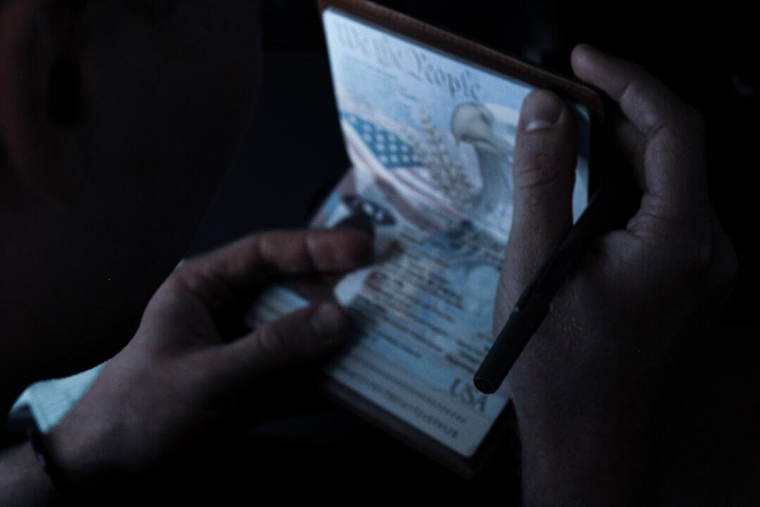 Falsidade ideologica e documental inline 1 509537 1785427814 Pessoa segurando um documento com a águia americana, possivelmente um passaporte.