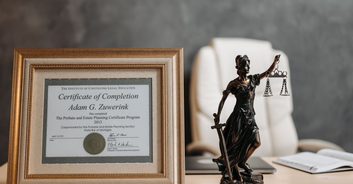 Escritório com certificado de conclusão e estátua da justiça em destaque.