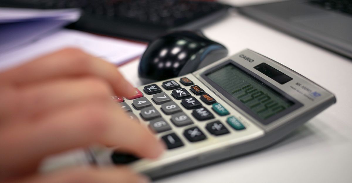 Mão digitando em uma calculadora, indicando cálculos financeiros pessoais.