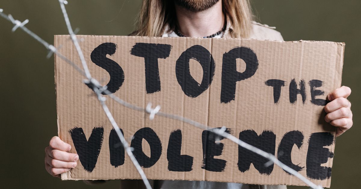 Pensao rapida como a nova lei protege financeiramente vitimas de violencia inline 2 482474 1785145107 Pessoa segurando um cartaz com a mensagem 'stop the violence' em frente a arame farpado.
