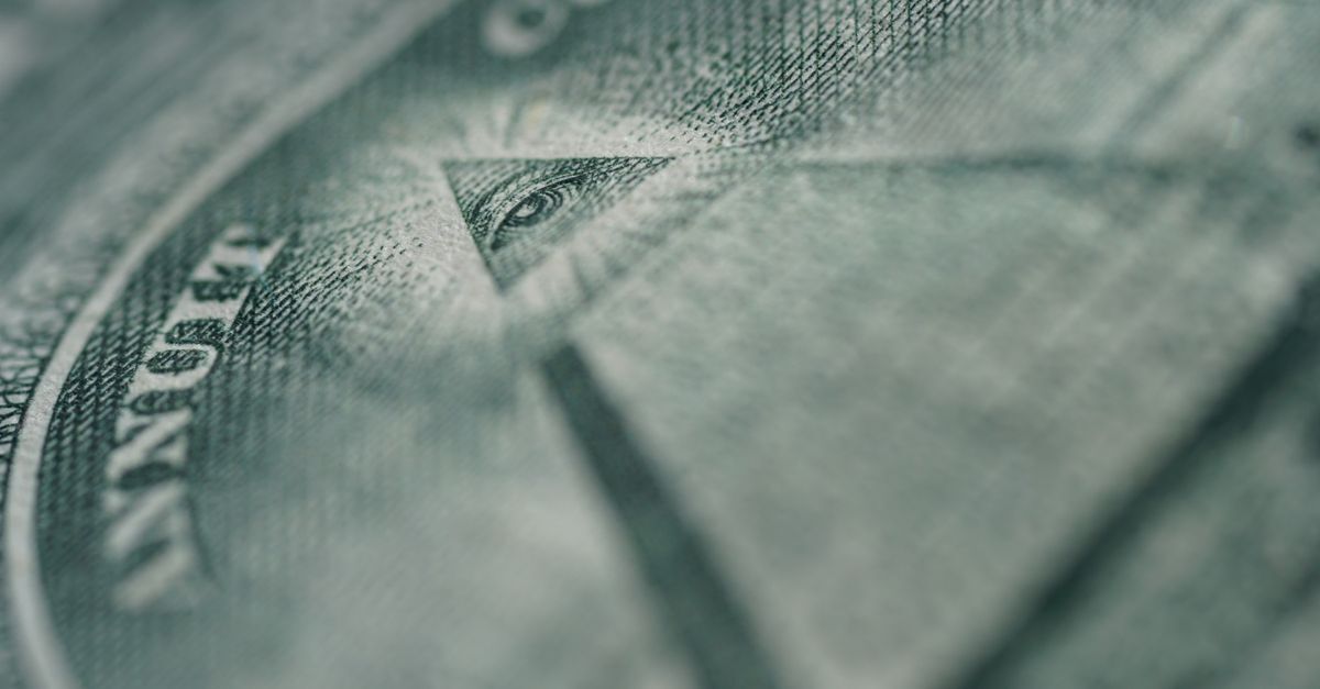 Detalhe de um símbolo financeiro com olho no topo de uma pirâmide.