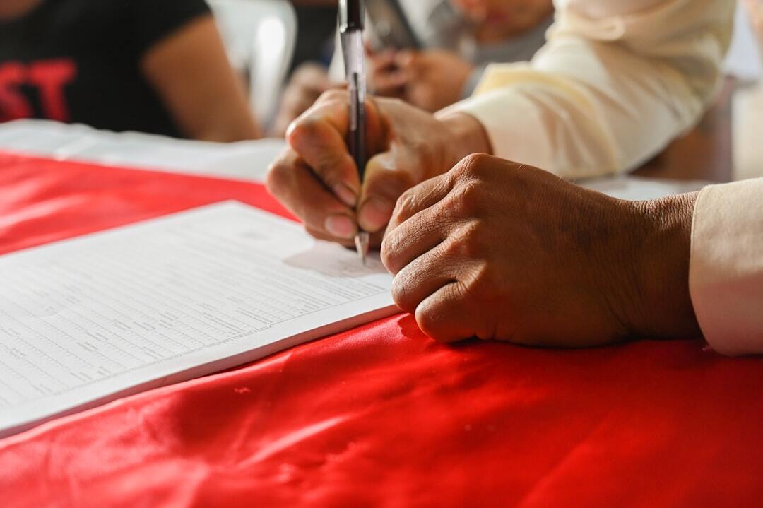 Property division in international divorce with a brazilian spouse inline 1 331517 1783037788 Pessoa escrevendo em um documento sobre uma mesa vermelha. — foto: sollange brenis