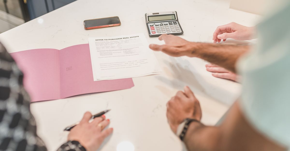Taxes and costs when buying property in brazil itbi cartorio registry inline 2 369387 1783518100 Pessoas reunidas ao redor de uma mesa analisando documentos, contrato e uma calculadora.