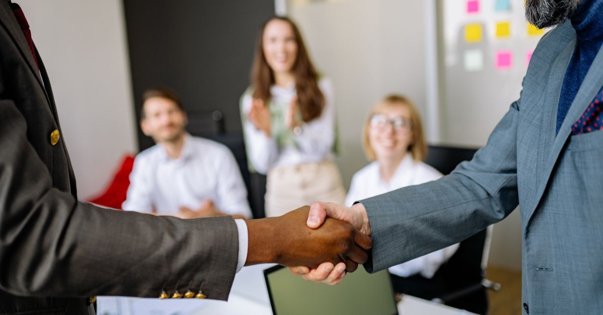 Profissionais em reunião de negócios, apertando mãos em ambiente de escritório.