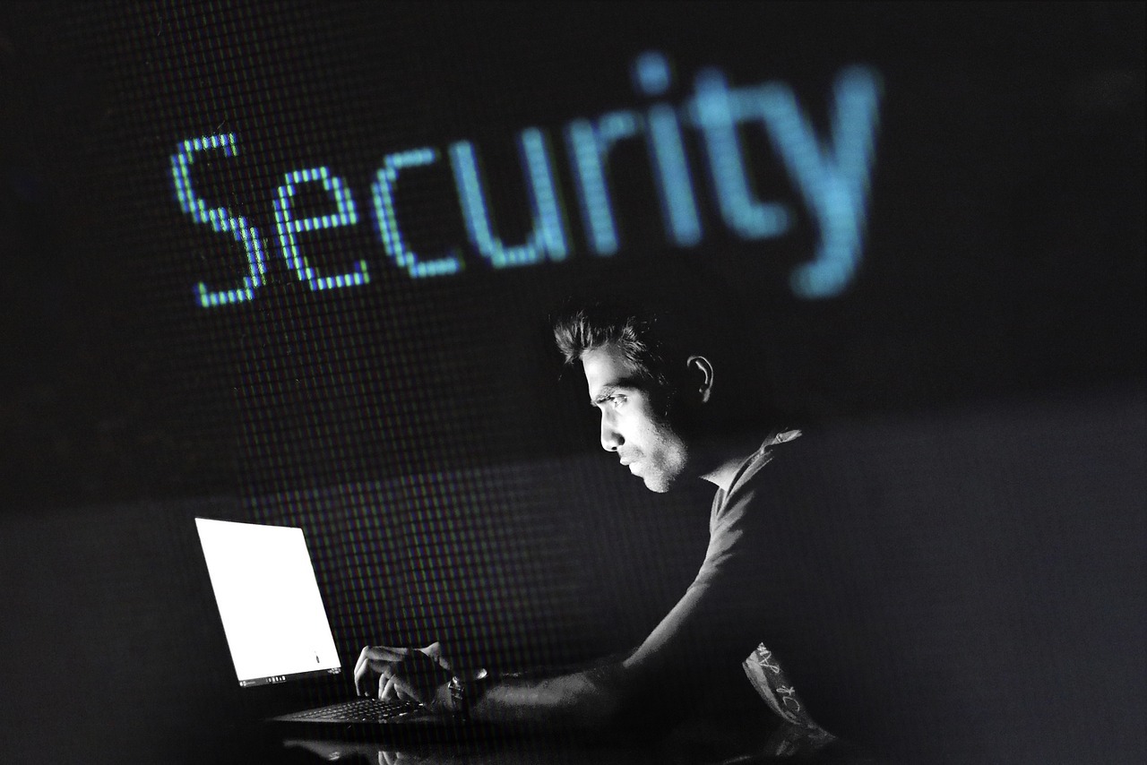 Vazamento de fotos por ia novas regras protegem cidadaos inline 1 462569 1785238815 Homem olhando para um laptop em um ambiente escuro, com a palavra 'security' iluminada ao fundo.