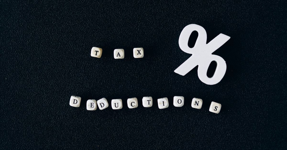 13o salario inline 1 617291 1786718091 Letras brancas em cubos sobre fundo escuro, mostrando 'tax' e 'deductions' com um símbolo de porcentagem.