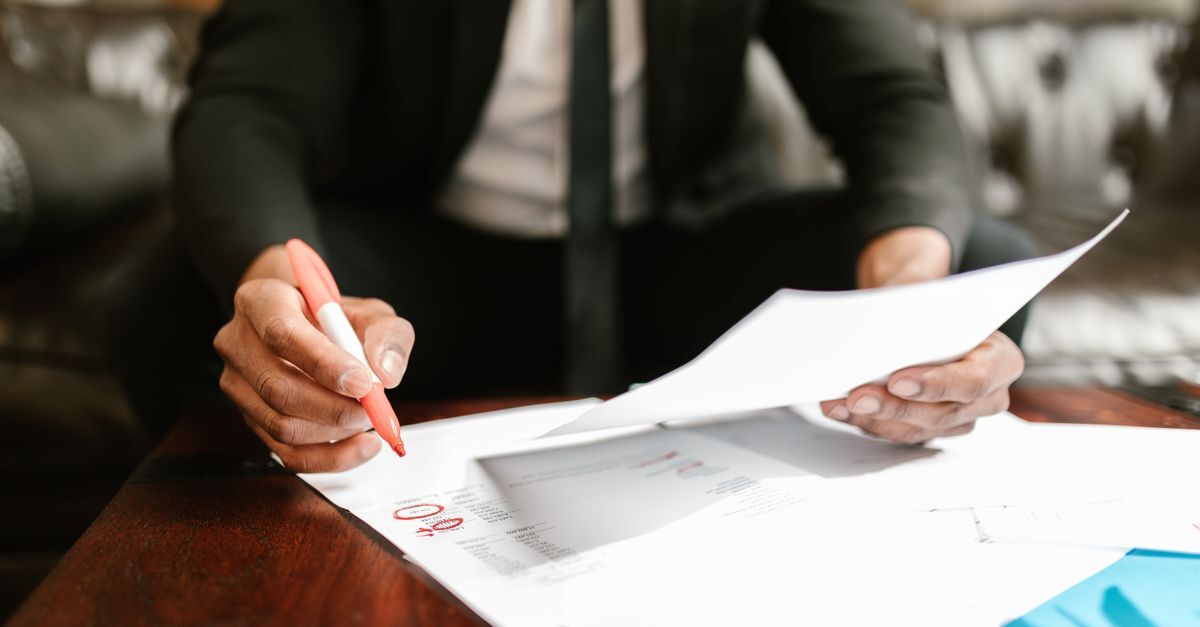 Apropriacao indebita previdenciaria inline 2 458581 1787501065 Pessoa assinando documentos em uma mesa, em ambiente de trabalho.