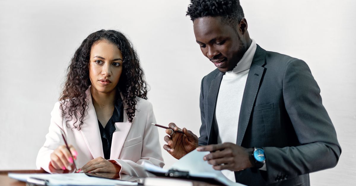 Brazil immigration compliance for companies hiring foreign workers inline 2 547077 1785947676 Dois profissionais em blazer discutindo documentos em uma mesa.