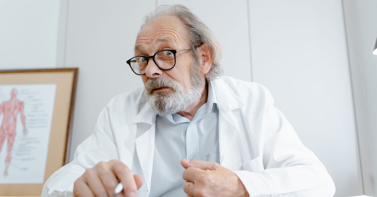 Cid d46 sindrome mielodisplasica afastamento auxilio doenca e aposentadoria inline 2 633054 1786885479 Médico idoso em consultório, com diagrama médico ao fundo.