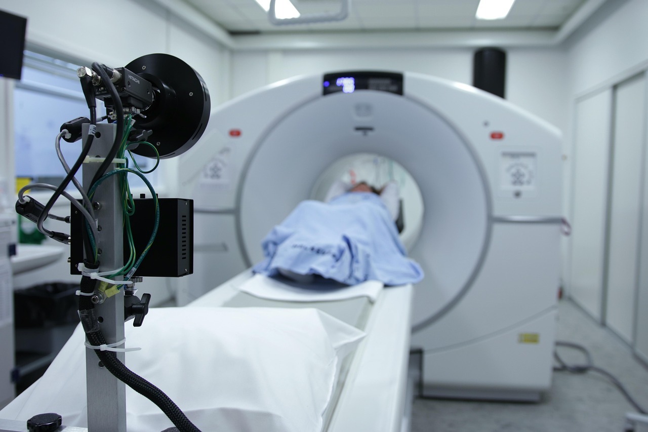 Pessoa em uma cama de rm, coberta com uma toalha azul, em um ambiente hospitalar.