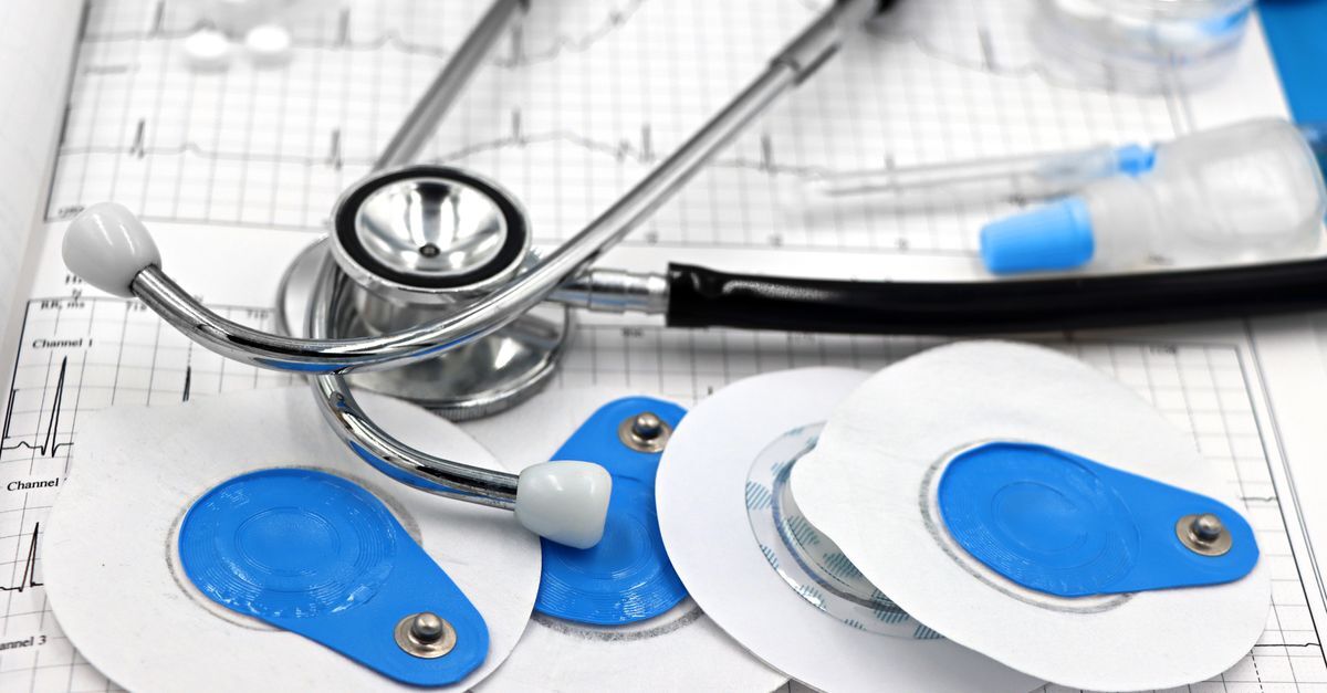 Equipamentos médicos, como um estetoscópio e placas de marcapasso, sobre um gráfico de ecg.
