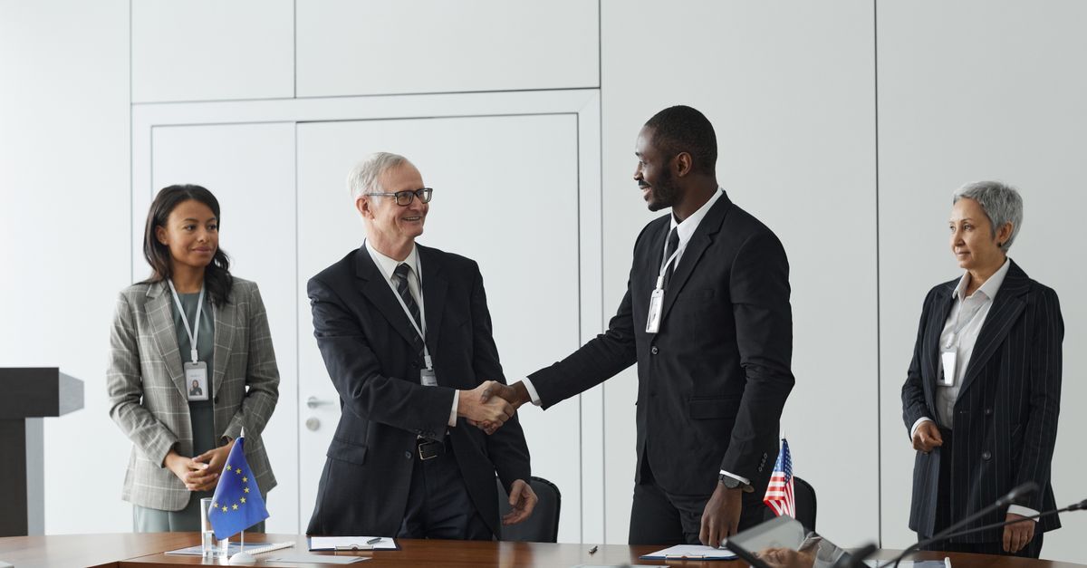 Company formation for foreigners in brazil inline 2 96415 1786811662 Quatro profissionais em um ambiente de escritório, dois em aperto de mãos, sugerindo uma reunião de negócios.