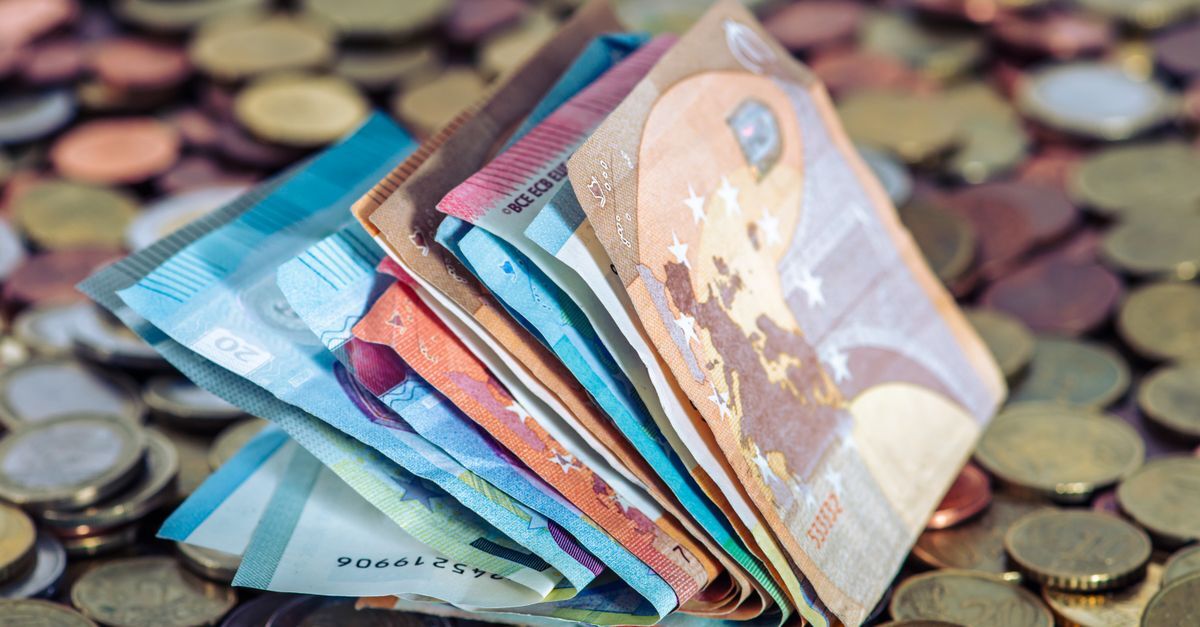 Pacote de cédulas de diferentes valores e moedas sobrepostas a moedas de diversos tamanhos e cores.