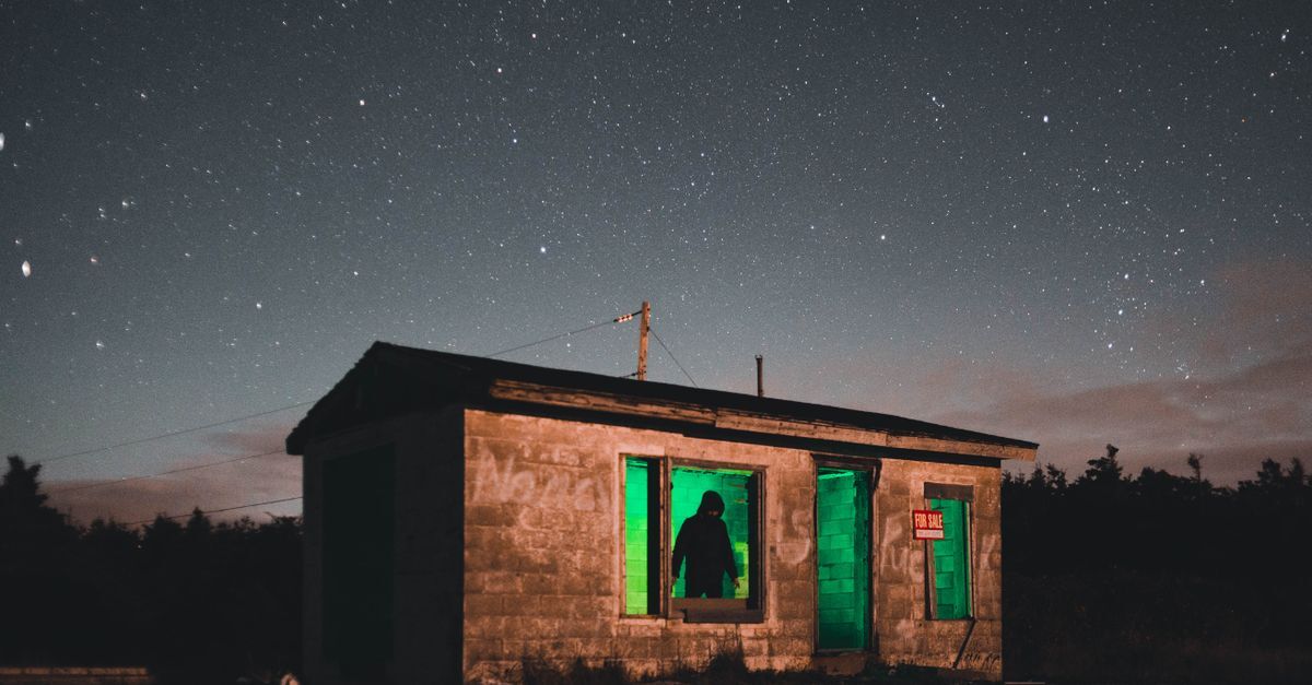 Crimes contra o patrimonio inline 1 326327 1785945900 Casa abandonada com luzes verdes e uma figura sombria, sugerindo um ato de furto sob a noite estrelada.
