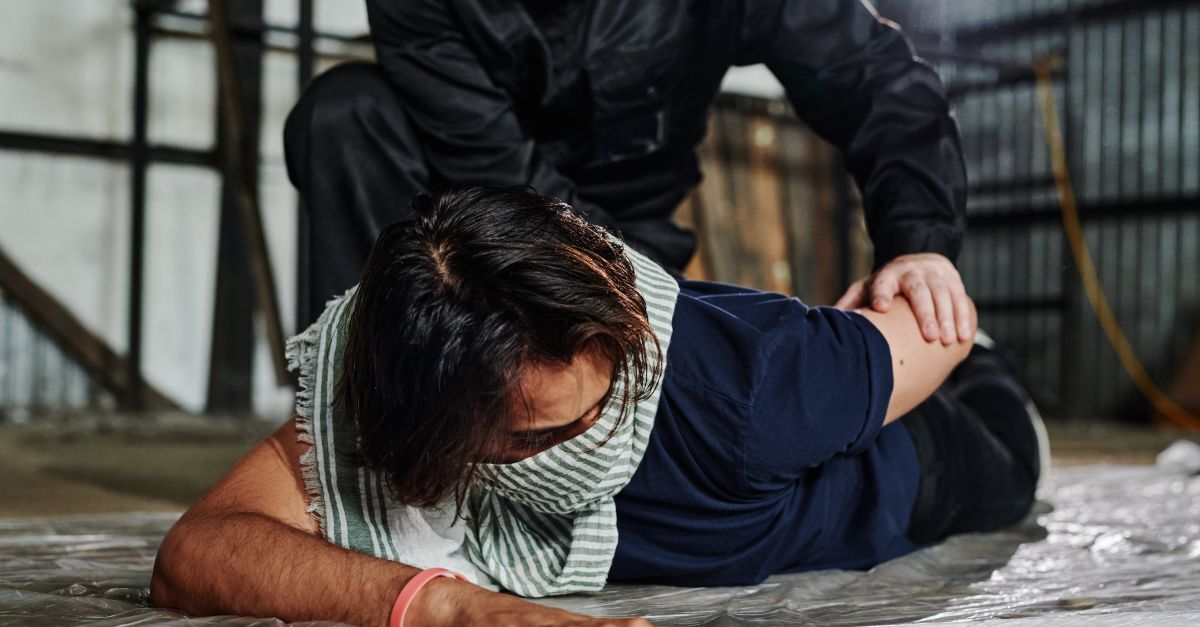 Crimes contra o patrimonio inline 2 326327 1785945913 Homem deitado no chão com outra pessoa em cima dele, em ambiente industrial.