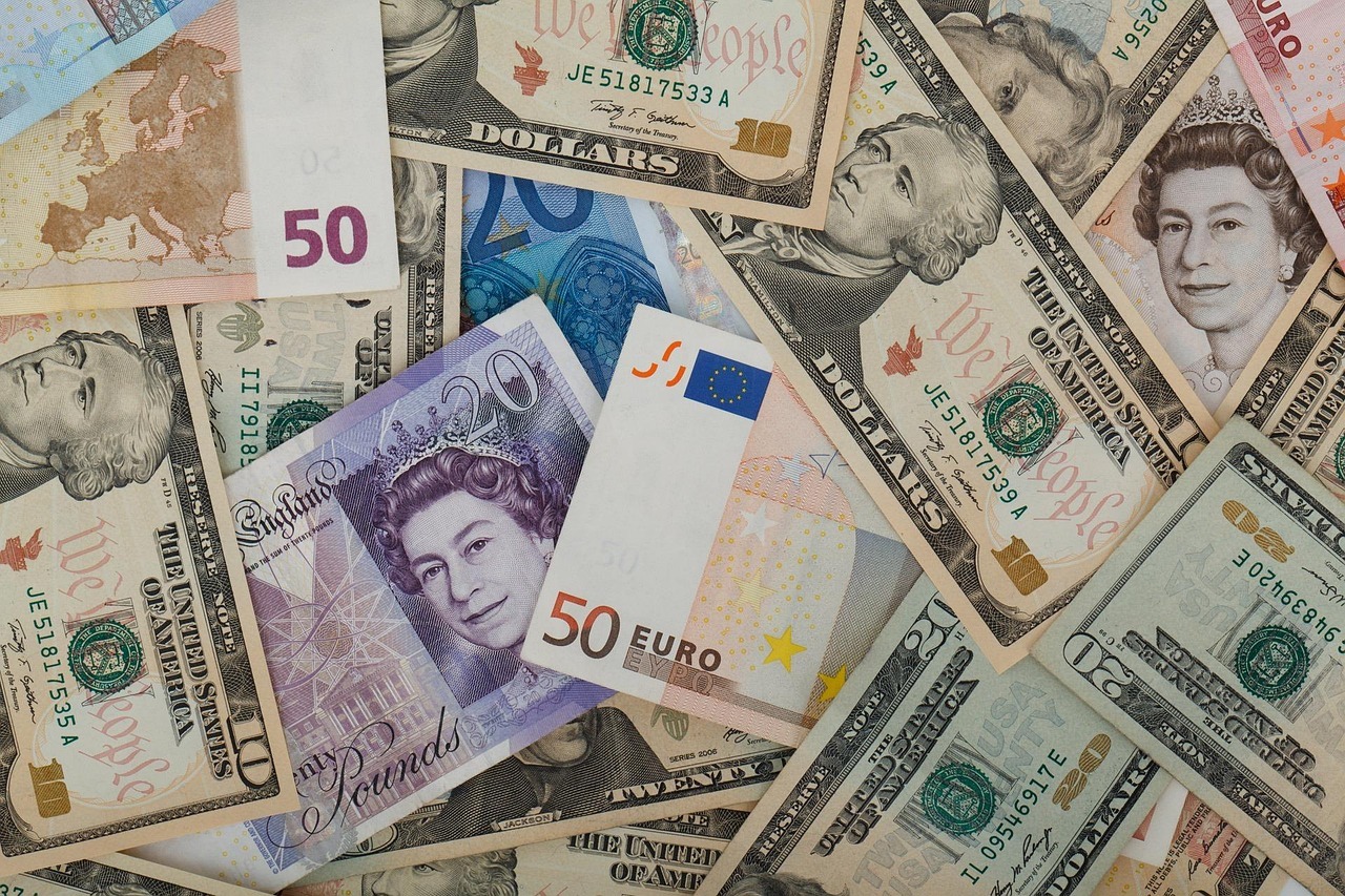 Montagem de cédulas de diversos países, incluindo dólares, euros e libras, sobre uma superfície.