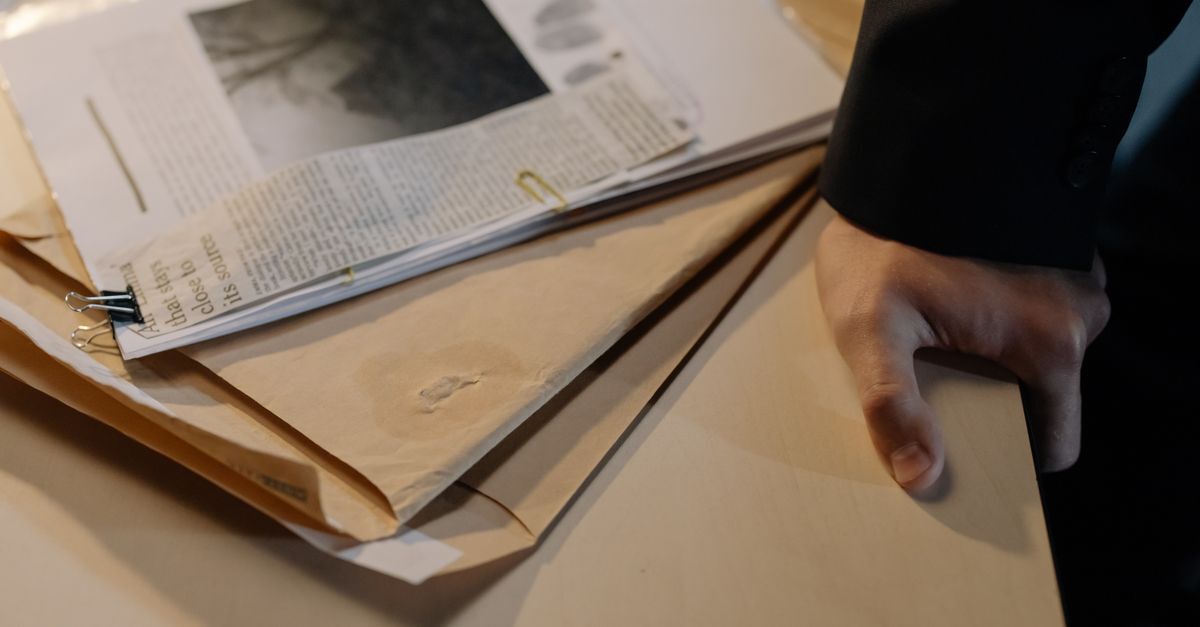 Pessoa segurando documentos em uma mesa, situações comuns em casos de crimes financeiros.